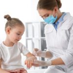 Doctor Applying Cream Onto Skin Of Little Girl With Chickenpox
