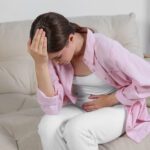 Young Woman Suffering From Cystitis On Sofa At Home